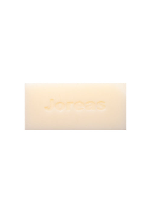 Creamy rectangular cleansing bar with embossed text on a white background